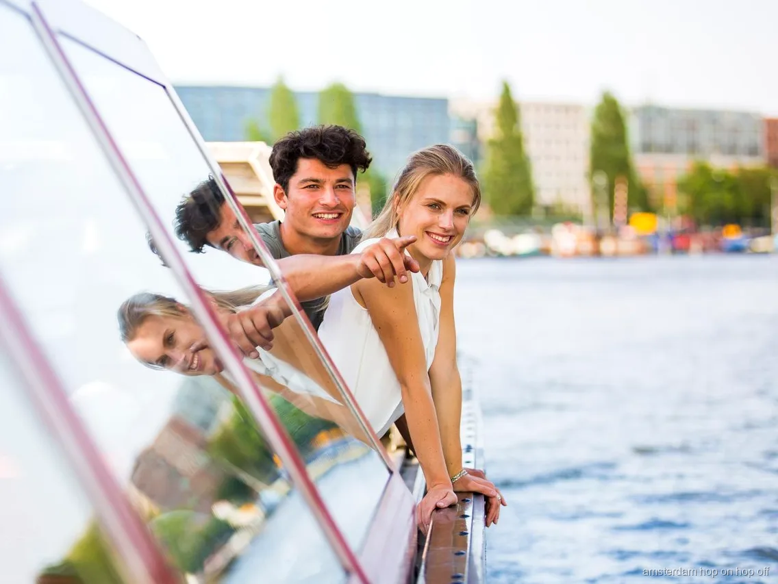 Passagers sur le bateau hop-on hop-off d'Amsterdam devant des maisons de canal historiques