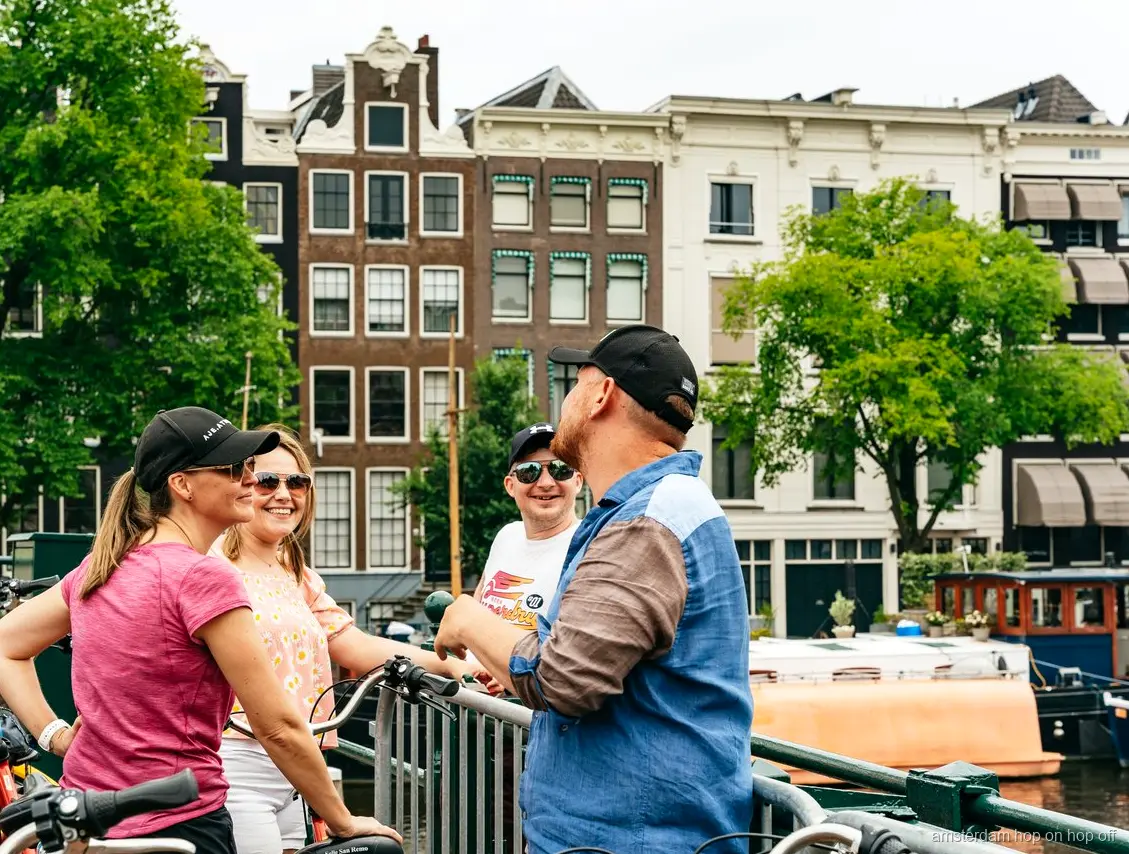 Cyclists on the Big Bike Tour passing a historic Amsterdam canal house