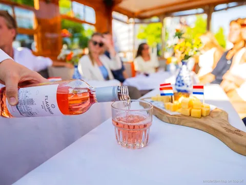 Patrón local guiando un crucero por los canales de Amsterdam junto a casas históricas