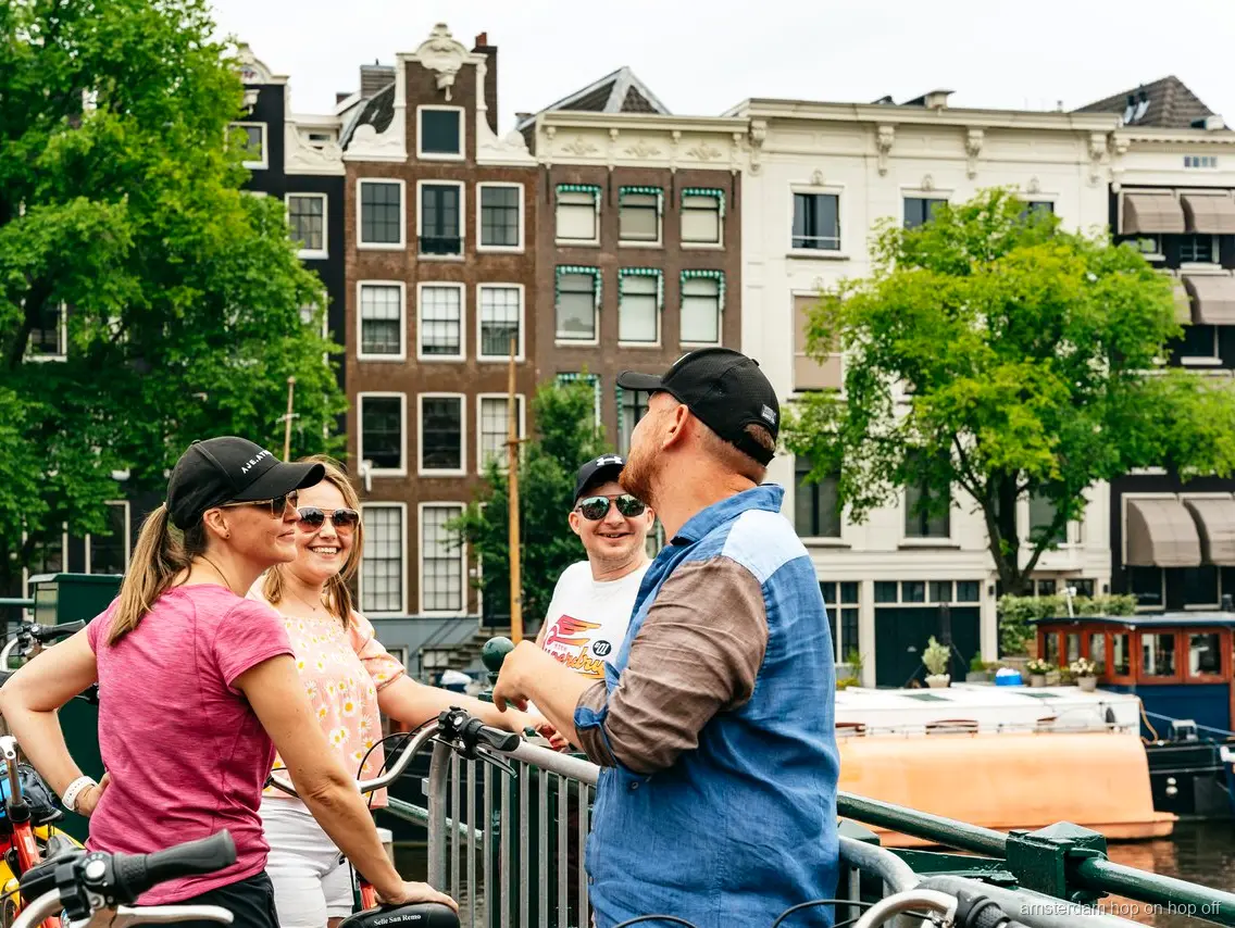 Radfahrer der Großen Fahrradtour Amsterdam an einem historischen Grachtenhaus