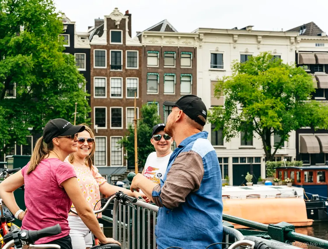 Fietsers op de Grote Fietstour langs een historisch Amsterdams grachtenpand